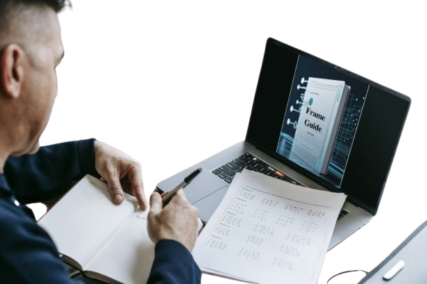 Person working at a desk with a laptop and notebook, reviewing a 'Frame Guide'.